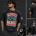 A man wearing a black graphic t-shirt with a 'Freedom Rebel Energy' motorcycle print, shown in a three-panel collage against a dark gray metal wall with a motorcycle.