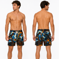 A male model shown from the front and back wearing swim trunks with a bold abstract print in blue, orange, white, and black on a light gray studio background.
