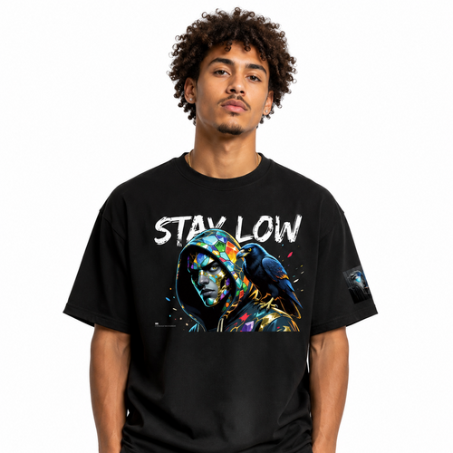 A man wearing a black graphic t-shirt with a colorful hooded character print and the text 'STAY LOW' across the chest, paired with black sweatpants against a plain white background.