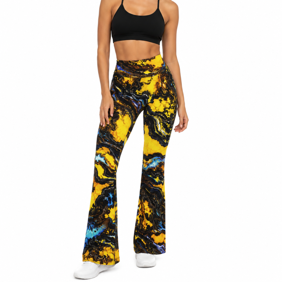 A woman modeling high-waisted flare pants with a bold yellow, black, and blue marble pattern, paired with a black sports bra and white sneakers, against a plain white background.
