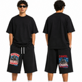 A model shown from the front and back wearing a black oversized t-shirt and black shorts with graphic prints. The front view shows a graphic on the left leg reading 'FREEDOM Rebel Energy' and the back view shows a graphic on the right leg reading 'CANCEL CHADS REBEL ENERGY'.