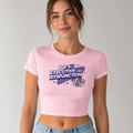 A woman wearing a light pink crop top t-shirt with a purple and white graphic that reads 'EXECUTIVE USA DYSFUNCTION' and a cartoon character, paired with light blue jeans, against a plain light gray background.
